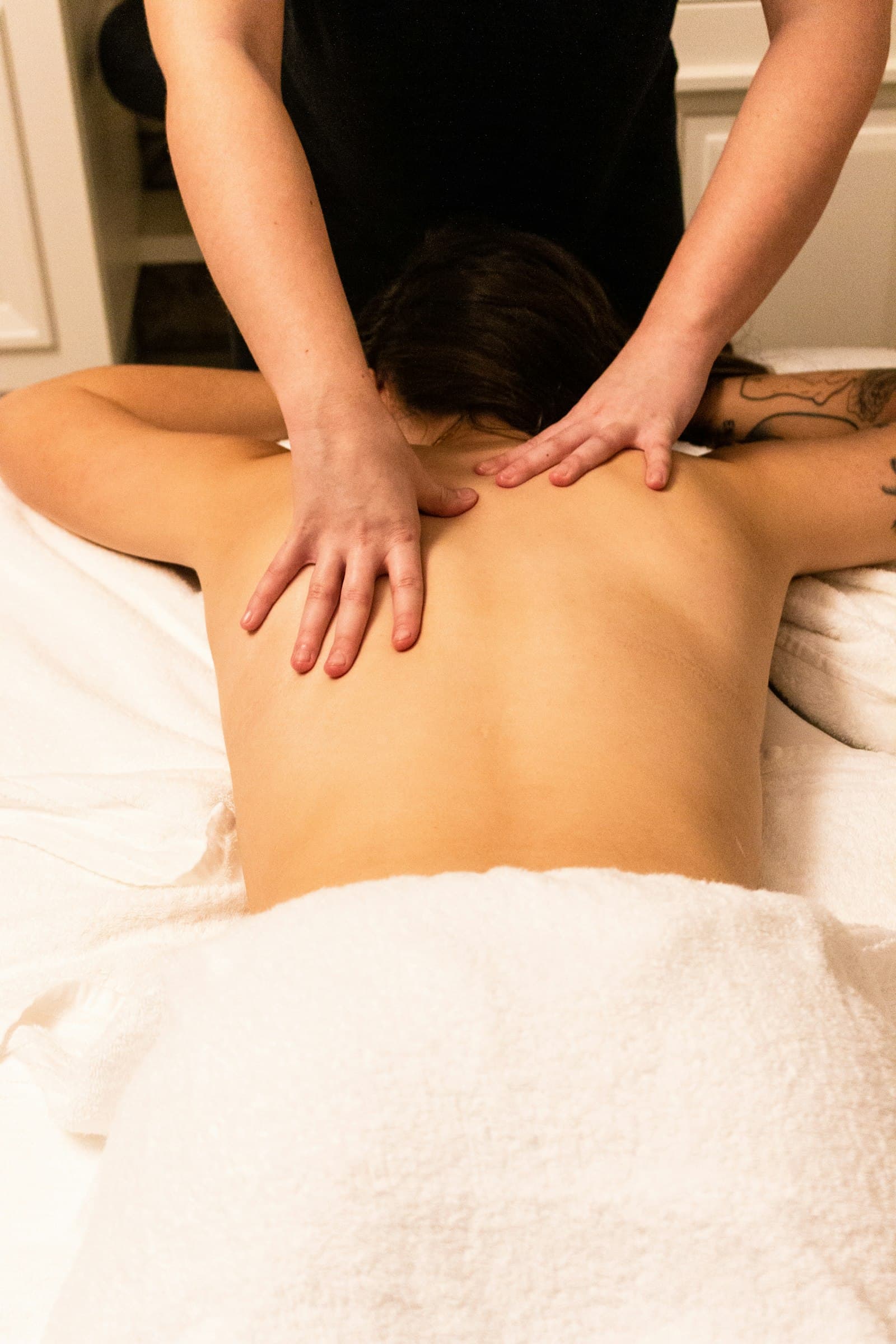 Registered massage therapist treating a client's upper back and shoulders